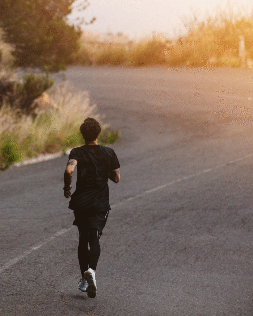 Pessoa correndo sozinha em estrada ao amanhecer simbolizando disciplina, foco e constância no caminho do sucesso.